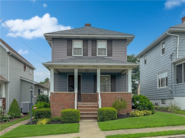 979 9th St, Taylor Twp, PA 16160 - american foursquare style home with a porch, brick siding, a chimney, a shingled roof, and a front yard