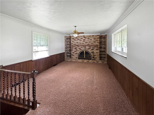 979 9th St, Taylor Twp, PA 16160 - unfurnished living room featuring wainscoting, wood walls, a fireplace, a ceiling fan, and carpet