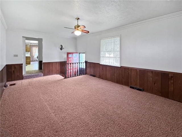 979 9th St, Taylor Twp, PA 16160 - carpeted empty room featuring wainscoting, wood walls, ornamental molding, ceiling fan, and a textured ceiling