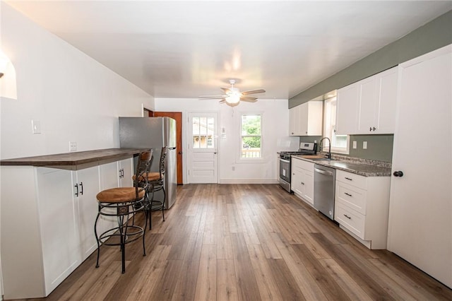 539 Park Ave, Monongahela, PA 15063 - kitchen featuring appliances with stainless steel finishes, wood-type flooring, a ceiling fan, white cabinets, and a kitchen bar