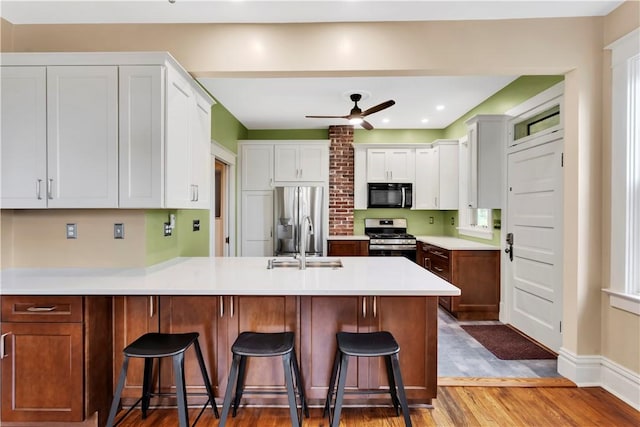 122 Haldane St, Crafton, PA 15205 - kitchen featuring stainless steel appliances, a peninsula, wood finished floors, a kitchen bar, and a ceiling fan