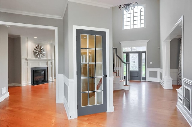 4127 Duckhorn Dr, Moon/Crescent Twp, PA 15108 - foyer featuring wood finished floors, a fireplace with flush hearth, a chandelier, a wainscoted wall, and stairs