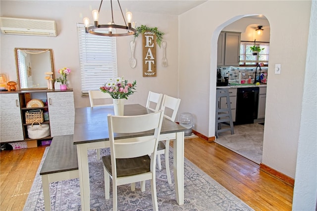 1109 N 2nd St, Jeannette, PA 15644 - dining space featuring an AC wall unit, light wood-style floors, a chandelier, and arched walkways