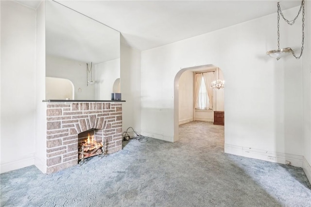 518 N Saint Clair St, East Liberty, PA 15206 - unfurnished living room with carpet floors, arched walkways, a stone fireplace, and a chandelier