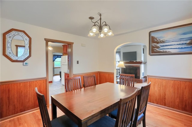 1009 Roselawn Ave, Harmony Twp, PA 15003 - dining area featuring arched walkways, a wainscoted wall, a fireplace, a chandelier, and wooden walls