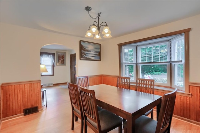 1009 Roselawn Ave, Harmony Twp, PA 15003 - dining area featuring a wainscoted wall, arched walkways, light wood-type flooring, a chandelier, and wood walls