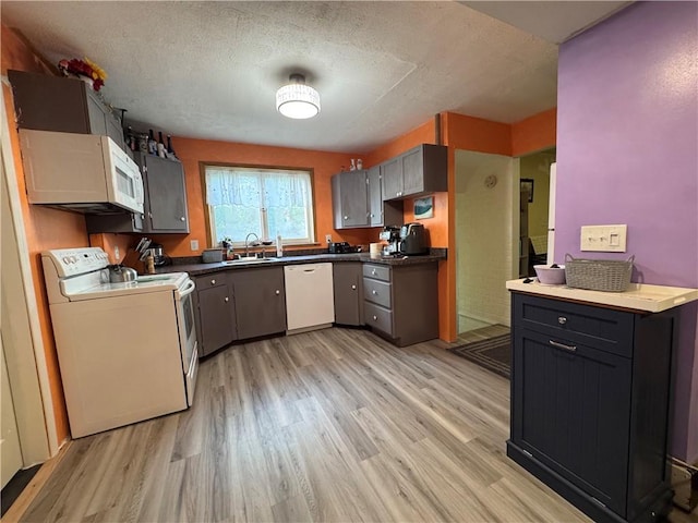 1077 Bechtol Ave, Sharon, PA 16146 - kitchen with white appliances, light wood-style flooring, dark countertops, and a textured ceiling