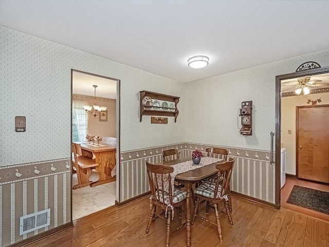 141 Clover Ln, Pine Twp, PA 15044 - dining space featuring wallpapered walls, wood finished floors, a chandelier, and wainscoting