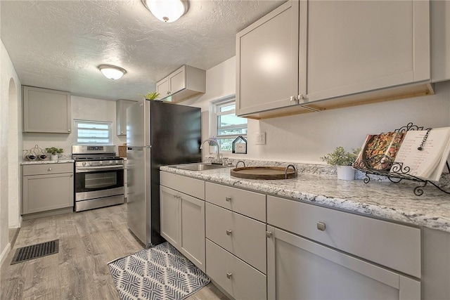 881 Main St, North Huntingdon, PA 15642 - kitchen with stainless steel appliances, light wood finished floors, a textured ceiling, healthy amount of natural light, and gray cabinetry