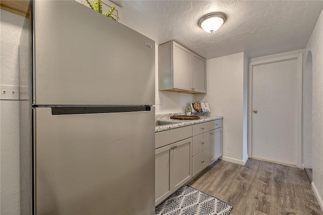 881 Main St, North Huntingdon, PA 15642 - kitchen featuring freestanding refrigerator, wood finished floors, and a textured ceiling