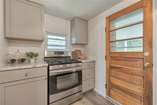 881 Main St, North Huntingdon, PA 15642 - kitchen with stainless steel gas stove, plenty of natural light, light wood finished floors, and gray cabinetry