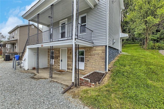 881 Main St, North Huntingdon, PA 15642 - view of side of home featuring a lawn, a patio area, a balcony, and stone siding