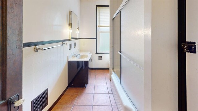 2945 Devlin St, Arlington, PA 15210 - full bathroom with vanity, tile patterned floors, tile walls, enclosed tub / shower combo, and wainscoting