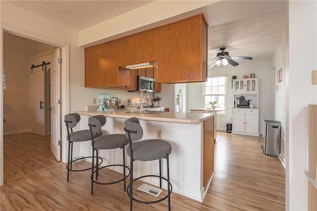 811 Sunset Cir Unit 811, Cranberry Twp, PA 16066 - kitchen featuring stainless steel microwave, light wood-style flooring, a peninsula, a barn door, and light countertops