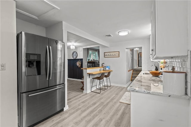 217 Westmont Rd, Ross Twp, PA 15237 - kitchen with stainless steel fridge, light wood-style flooring, white cabinets, decorative backsplash, and light stone counters