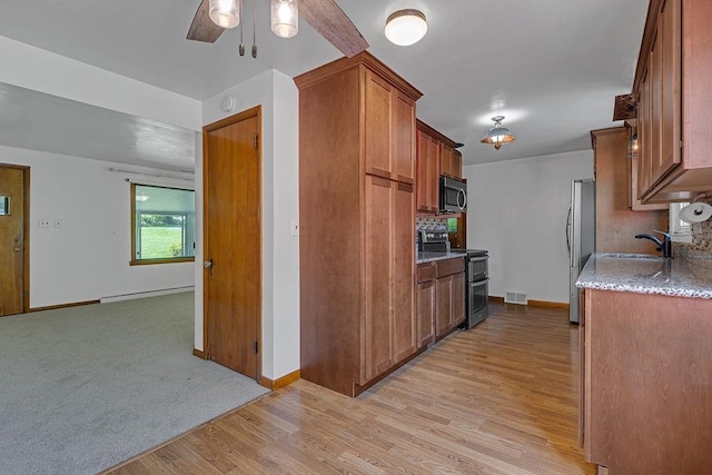 105 Eakin Dr, Brighton Twp, PA 15009 - kitchen featuring stainless steel appliances, a baseboard heating unit, a ceiling fan, light wood-style flooring, and brown cabinets