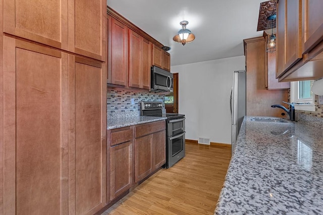 105 Eakin Dr, Brighton Twp, PA 15009 - kitchen featuring appliances with stainless steel finishes, backsplash, light wood-style floors, light stone counters, and brown cabinetry