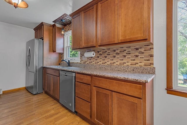 105 Eakin Dr, Brighton Twp, PA 15009 - kitchen with stainless steel appliances, backsplash, light wood-type flooring, light stone counters, and brown cabinets