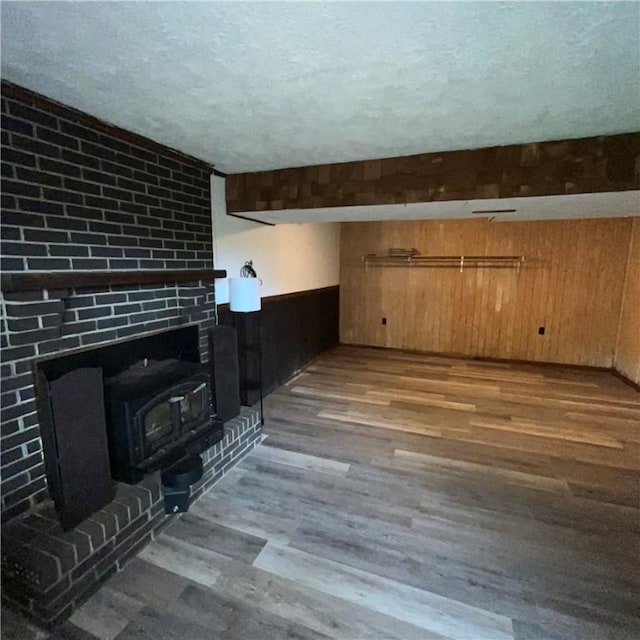 503 Bagdad Rd, Allegheny Twp, PA 15656 - unfurnished living room with wood finished floors, a wood stove, wooden walls, and a textured ceiling