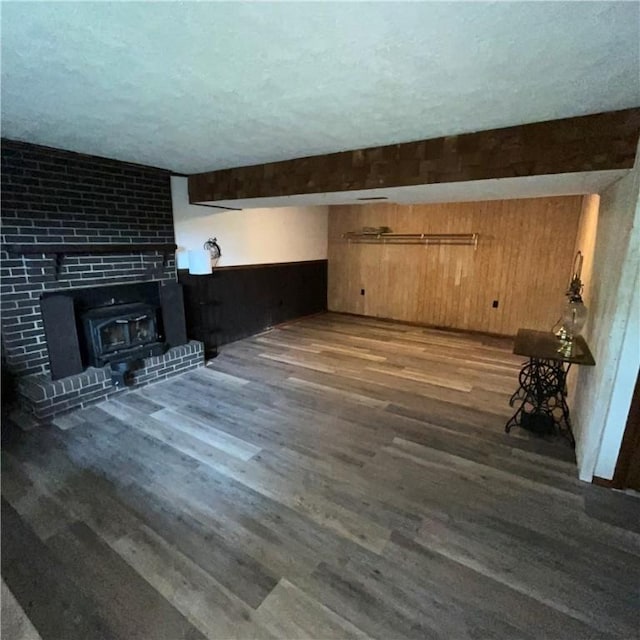 503 Bagdad Rd, Allegheny Twp, PA 15656 - unfurnished living room featuring wood finished floors, a textured ceiling, wood walls, and a wood stove
