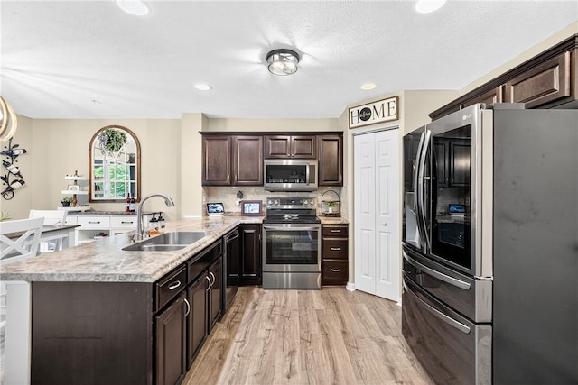 2000 Moccasin Dr, South Strabane, PA 15301 - kitchen featuring appliances with stainless steel finishes, a peninsula, dark brown cabinetry, light wood-style flooring, and light countertops
