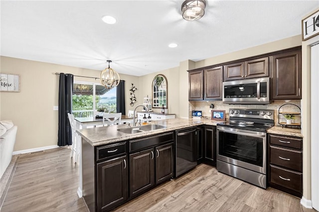 2000 Moccasin Dr, South Strabane, PA 15301 - kitchen featuring appliances with stainless steel finishes, a peninsula, a chandelier, light wood-type flooring, and backsplash