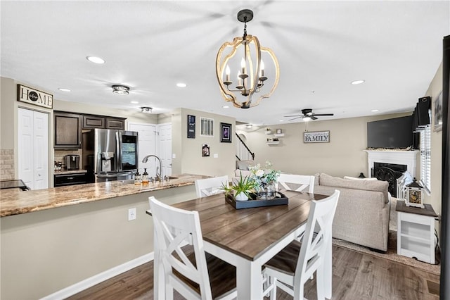 2000 Moccasin Dr, South Strabane, PA 15301 - dining space with wood finished floors, a fireplace, a chandelier, stairway, and ceiling fan