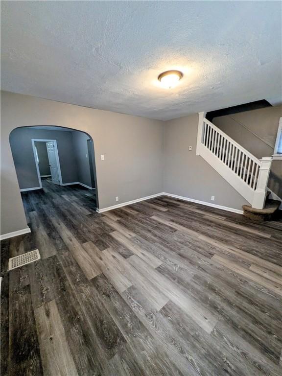 1819 Scott St, Mckeesport, PA 15132 - unfurnished living room with arched walkways, a textured ceiling, wood finished floors, and stairs