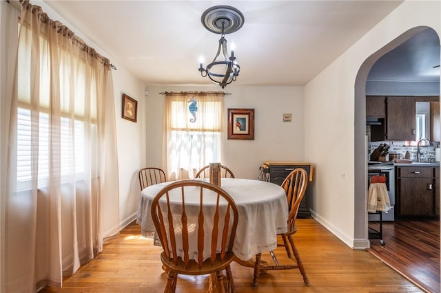 1029 3rd St, Baden, PA 15005 - dining room featuring arched walkways, light wood-type flooring, and a chandelier
