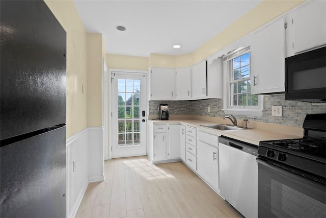 2324 Mcaleer Rd, Franklin Park, PA 15143 - kitchen with black appliances, light countertops, white cabinetry, backsplash, and a wainscoted wall