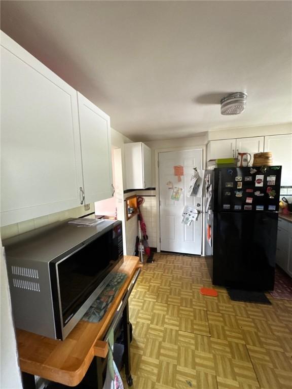 155 Roosevelt Ave, Stowe Twp, PA 15136 - kitchen with freestanding refrigerator, stainless steel microwave, and white cabinetry
