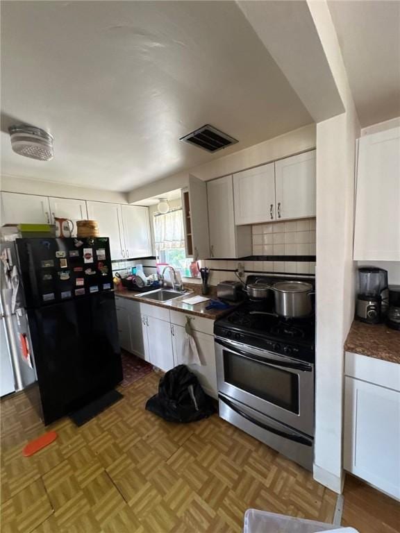 155 Roosevelt Ave, Stowe Twp, PA 15136 - kitchen with stainless steel gas range, freestanding refrigerator, white cabinetry, dark countertops, and tasteful backsplash