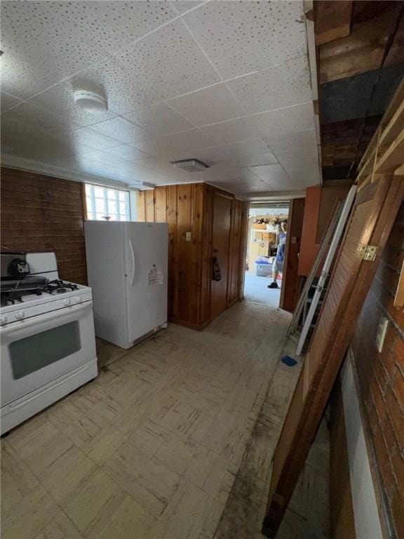 155 Roosevelt Ave, Stowe Twp, PA 15136 - kitchen with white appliances, light flooring, brown cabinets, a drop ceiling, and wooden walls