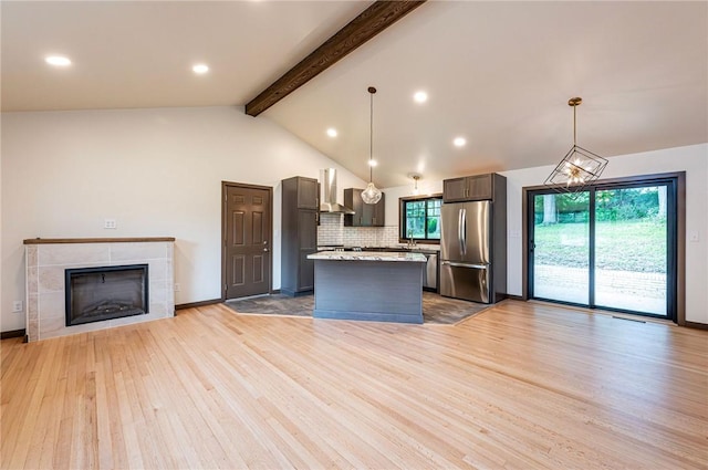 5 Bel Aire Dr, Murrysville, PA 15626 - kitchen featuring freestanding refrigerator, wall chimney exhaust hood, light wood finished floors, decorative backsplash, and a center island