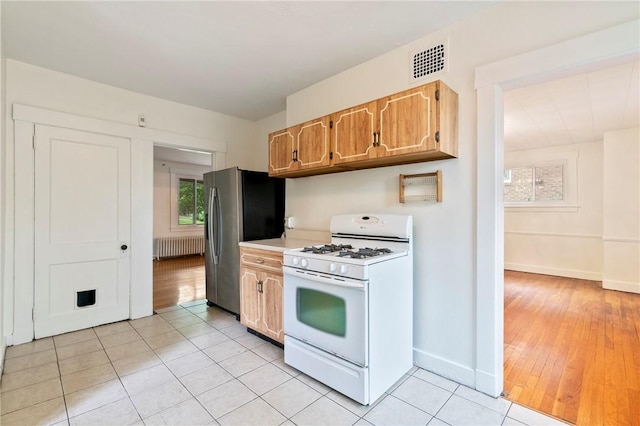 3001 Mount Allister Rd, Observatory Hill, PA 15214 - kitchen featuring white gas range, radiator, stainless steel fridge with ice dispenser, light countertops, and light tile patterned floors