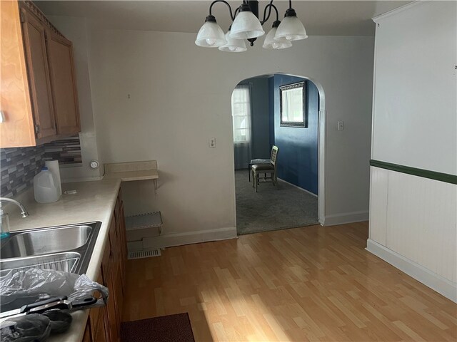 121 W Midland Ave, Midland Boro, PA 15059 - kitchen featuring arched walkways, a chandelier, light wood-style floors, tasteful backsplash, and light countertops