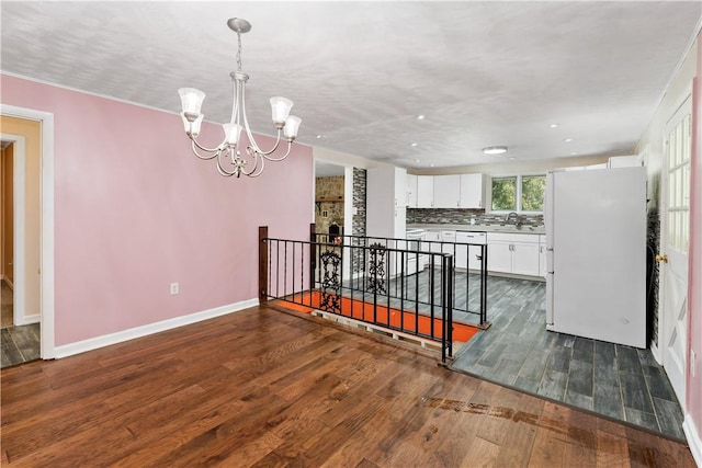 5342 Pleasant Unity Rd, Latrobe, PA 15650 - kitchen with white appliances, a chandelier, white cabinets, dark wood-style flooring, and backsplash