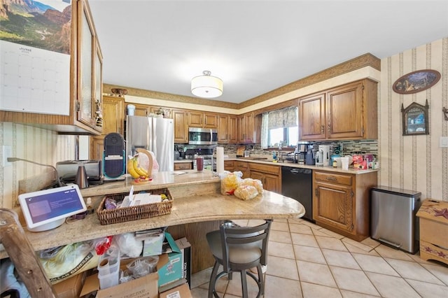 334 Park St, North Union Twp, PA 15401 - kitchen featuring appliances with stainless steel finishes, wallpapered walls, light countertops, brown cabinets, and a peninsula