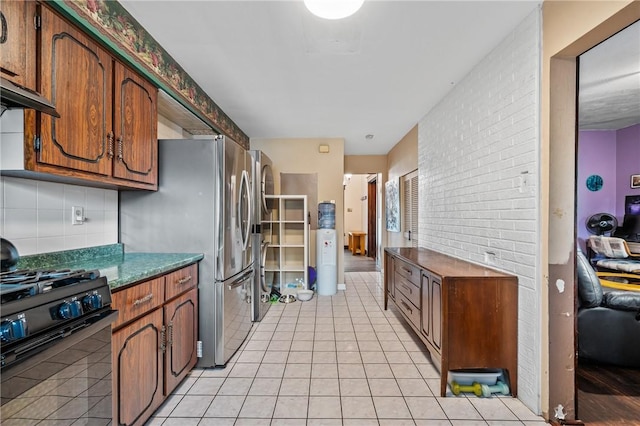 1860 Jancey St, Morningside, PA 15206 - kitchen featuring black range with gas cooktop, light tile patterned floors, tasteful backsplash, brown cabinets, and freestanding refrigerator