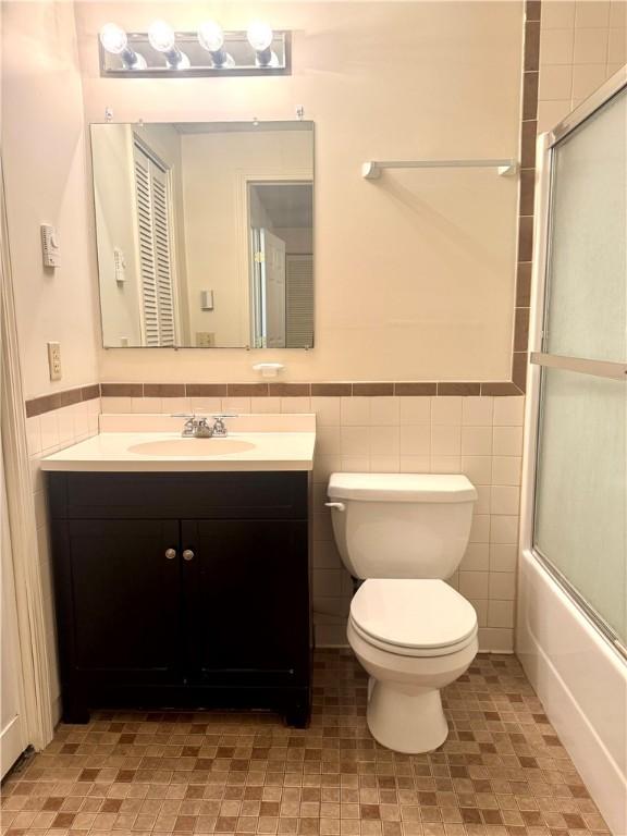 230 E Water St, Slippery Rock Boro, PA 16057 - full bath featuring vanity, a wainscoted wall, tile walls, and enclosed tub / shower combo
