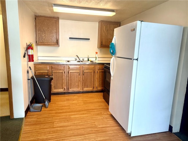 230 E Water St, Slippery Rock Boro, PA 16057 - kitchen with freestanding refrigerator, black range with electric stovetop, light wood-style floors, and brown cabinets