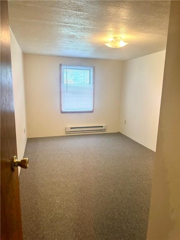 230 E Water St, Slippery Rock Boro, PA 16057 - unfurnished room with a baseboard heating unit, carpet floors, and a textured ceiling