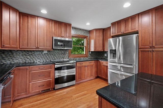 362 Ridge Rdg, Jackson Twp, PA 16063 - kitchen with stainless steel appliances, light wood finished floors, decorative backsplash, brown cabinetry, and dark stone countertops