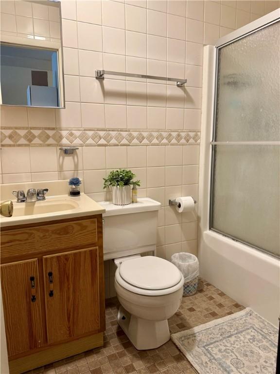 250 E Water St, Slippery Rock Boro, PA 16057 - bathroom featuring vanity, combined bath / shower with glass door, tile walls, and tile patterned floors