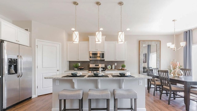 326 Stately Ct, Adams Twp, PA 16046 - kitchen with stainless steel appliances, light wood-style flooring, decorative backsplash, an island with sink, and white cabinets