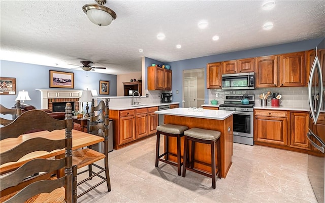 489 Jenny Dr, Richland, PA 15044 - kitchen with appliances with stainless steel finishes, a ceiling fan, a center island, brown cabinets, and light countertops
