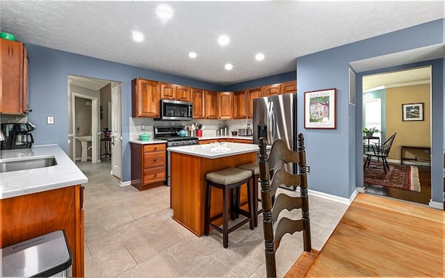 489 Jenny Dr, Richland, PA 15044 - kitchen featuring stainless steel appliances, light countertops, a kitchen island, a kitchen breakfast bar, and brown cabinetry
