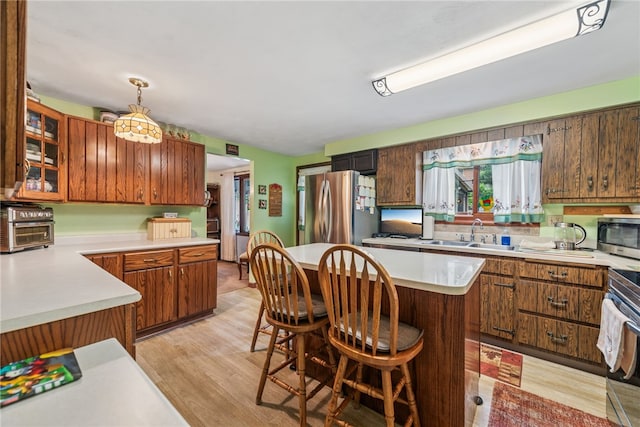 982 Braddock Rd, Forest Hills Boro, PA 15221 - kitchen with appliances with stainless steel finishes, light countertops, light wood-style flooring, hanging light fixtures, and a breakfast bar area