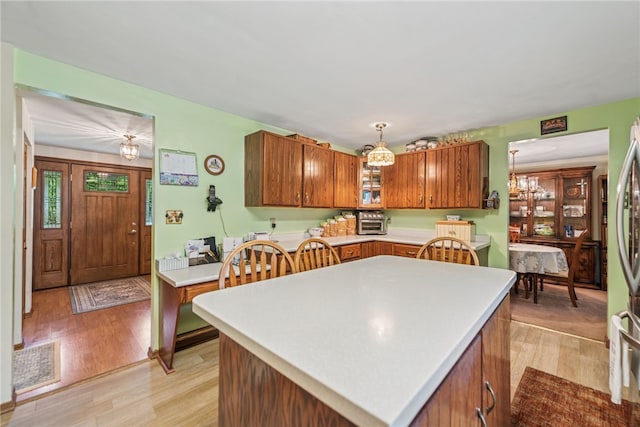 982 Braddock Rd, Forest Hills Boro, PA 15221 - kitchen featuring light wood-style flooring, brown cabinets, light countertops, glass insert cabinets, and a kitchen island