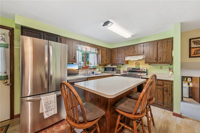 982 Braddock Rd, Forest Hills Boro, PA 15221 - kitchen with appliances with stainless steel finishes, under cabinet range hood, light countertops, a kitchen breakfast bar, and light wood-style floors